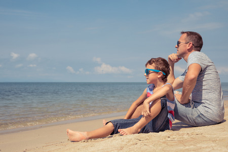 Father and  son playing on the beach at the summer day time. People having fun outdoors. Concept of summer vacation and friendly family.の写真素材