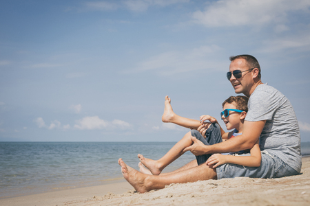 Father and  son playing on the beach at the summer day time. People having fun outdoors. Concept of summer vacation and friendly family.の写真素材