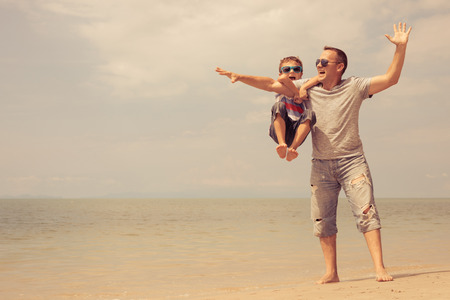 Father and  son playing on the beach at the summer day time. People having fun outdoors. Concept of summer vacation and friendly family.の写真素材