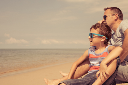 Father and  son playing on the beach at the summer day time. People having fun outdoors. Concept of summer vacation and friendly family.の写真素材