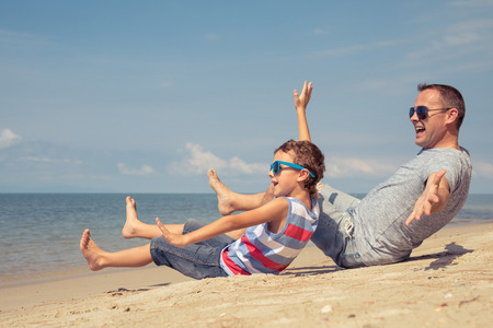 Father and  son playing on the beach at the summer day time. People having fun outdoors. Concept of summer vacation and friendly family.の写真素材