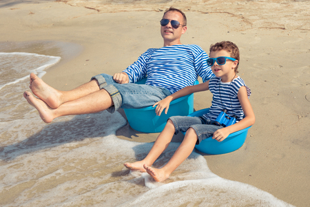 Father and  son playing on the beach at the day time. People having fun outdoors. Concept of summer vacation and friendly family.の写真素材