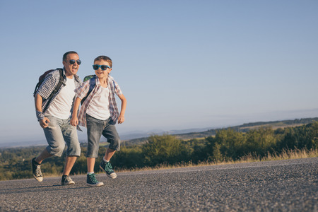 Father and son running on the road at the day time. Concept of tourism.の写真素材