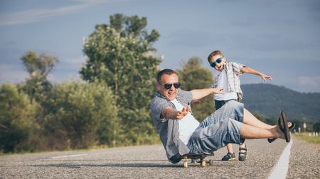 Father and son playing on the road at the day time. People having fun outdoors. Concept of friendly family.の写真素材
