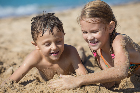 Happy children playing on the beach at the day time. Two Kids having fun outdoors. Concept of summer vacation and friendly family.の写真素材