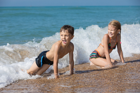Happy children playing on the beach at the day time. Two Kids having fun outdoors. Concept of summer vacation and friendly family.の写真素材