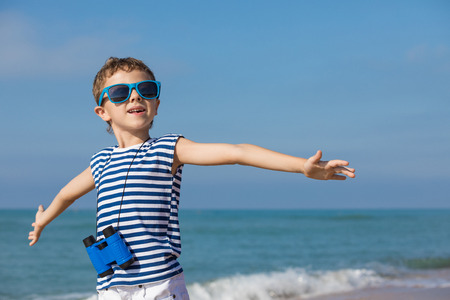 One happy little boy playing on the beach at the day time. He are dressed in sailor's vest. Kid having fun outdoors. Concept of sailor on vacation.の写真素材