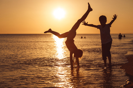 Happy children playing on the beach at the sunset time. Two Kids having fun outdoors. Concept of summer vacation and friendly family.の写真素材