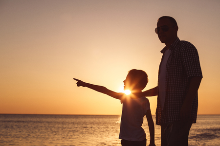 Father and son playing on the beach at the sunset time. People having fun outdoors.  Concept of happy vacation and friendly family.の写真素材
