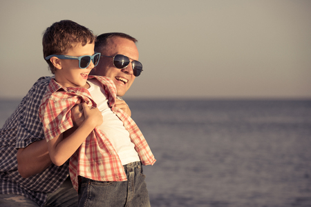 Father and son playing on the beach at the day time. People having fun outdoors.  Concept of happy vacation and friendly family.の写真素材