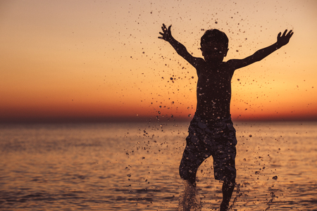 One happy little boy playing on the beach at the sunset time.  Kid having fun outdoors. Concept of summer vacation.の写真素材