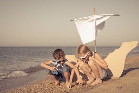 Happy children playing on the beach at the day time. Two Kids having fun outdoors. Concept of summer vacation and friendly family.の写真素材