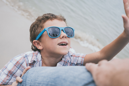 Father and son playing on the beach at the day time. People having fun outdoors.  Concept of happy...