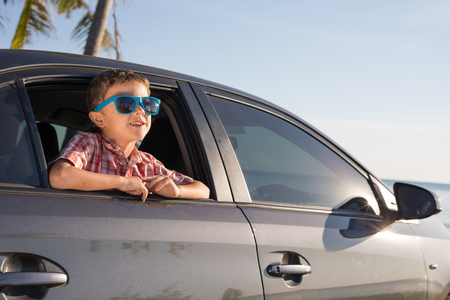 One happy little boy sitting in the car at the day time. Concept of summer vacation.の写真素材