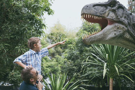 Happy father and son playing in the adventure dino park at the day time. People having fun outdoors. Concept of summer vacation and friendly family.の写真素材
