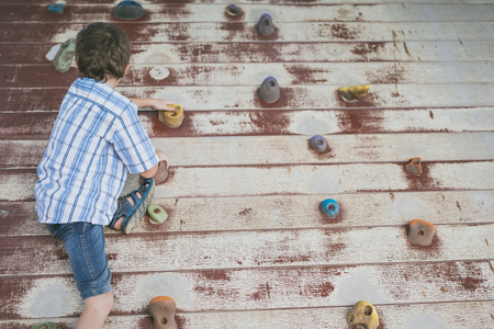 little boy climbing a rock wall outdoor. Concept of sport life.の写真素材