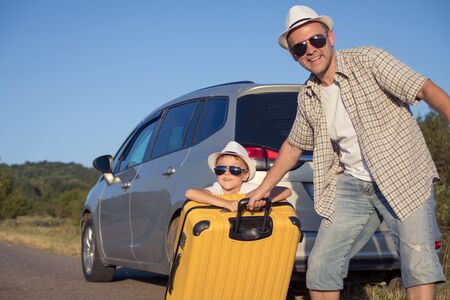 Happy father and son standing near the car at the day time. They look out the window. People having fun outdoors. Concept of the family is ready for travel.の写真素材