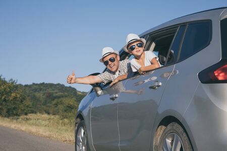 Happy father and son sitting in the car at the day time. They look out the window. People having fun outdoors. Concept of the family is ready for travel.の写真素材