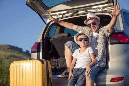 Happy father and son standing near the car at the day time. They look out the window. People having fun outdoors. Concept of the family is ready for travel.の写真素材