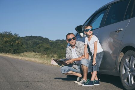 Happy father and son standing near the car at the day time. They look out the window. People having fun outdoors. Concept of the family is ready for travel.の写真素材