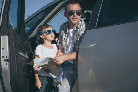 Happy father and son standing near the car at the day time. They look out the window. People having fun outdoors. Concept of the family is ready for travel.の写真素材