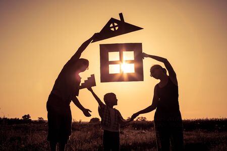 Happy family standing on the field at the sunset time. They build a house. Concept of friendly family.の写真素材
