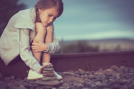 Portrait of young sad girl sitting outdoors  on the railway at the day time. Concept of sorrow.の写真素材