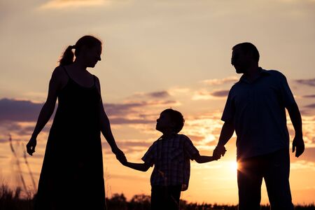 Happy family standing in the park at the sunset time. People having fun outdoors. Concept of friendly family.の写真素材