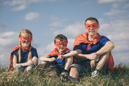 Father and children playing superhero at the day time. People having fun outdoors. Concept of friendly family.の写真素材