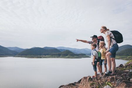 Happy family standing near the lake at the day time.  Concept of friendly family.