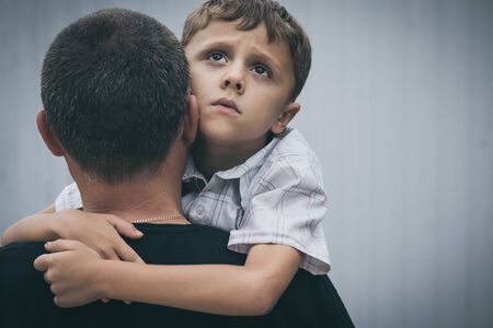 Portrait of young sad little boy and father standing outdoors at the day time. Concept of sorrow.の写真素材