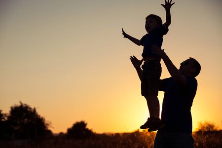 Father and son playing in the park at the sunset time. People having fun on the field. Concept of friendly family and of summer vacation.の写真素材