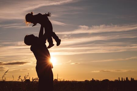 Father and son playing in the park at the sunset time. People having fun on the field. Concept of...