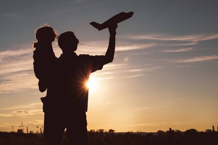 Father and son playing in the park at the sunset time. People having fun on the field. Concept of friendly family and of summer vacation.の写真素材