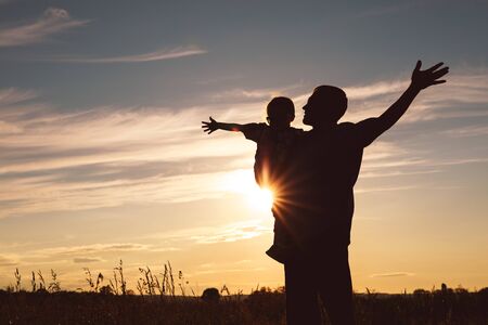 Father and son playing in the park at the sunset time. People having fun on the field. Concept of friendly family and of summer vacation.の写真素材