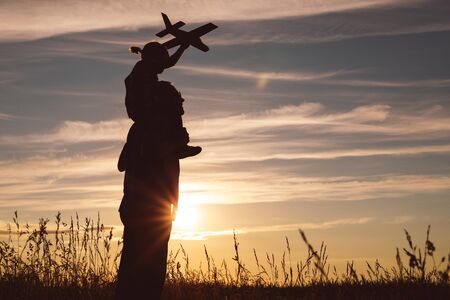Father and son playing in the park at the sunset time. People having fun on the field. Concept of...