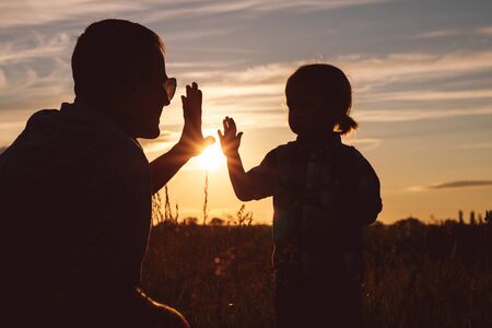 Father and son playing in the park at the sunset time. People having fun on the field. Concept of friendly family and of summer vacation.の写真素材