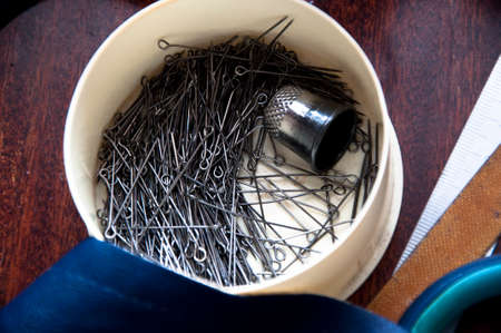 Closeup of sewing workshop tools of scissors rule needle minikin pin leather fabric lying on wooden...