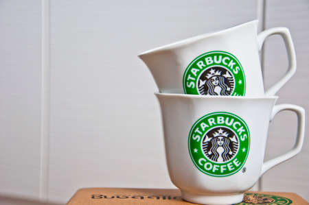 Kiev, Ukraine - February 16, 2016: Two ceramic shiny company white cups with stylish round green logo of Starbucks coffeehouse corporation on paper boxのeditorial素材