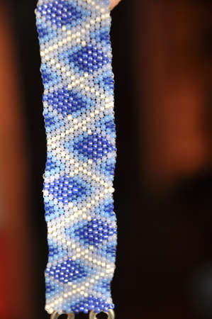 Bracelet fragment from small beads with ethnic ornament on a blurred background, texture and...