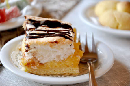 fresh cream cake closeup with chocolate sauce topping on plate with forkの写真素材