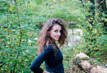 young sexy woman or girl with long hair on pretty face in black shirt in autumn seasonal green forest or wood with leaves on natural backgroundの写真素材
