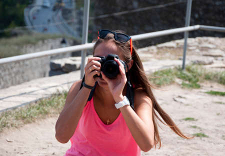 young woman or girl photographer with long brunette hair sunny day outdoor in sunglasses or glasses...