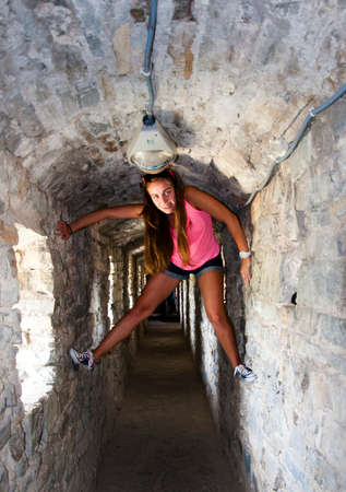 young woman or girl with pretty happy smiling face in pink summer vest and sunglasses in tunnel with stony wallの写真素材