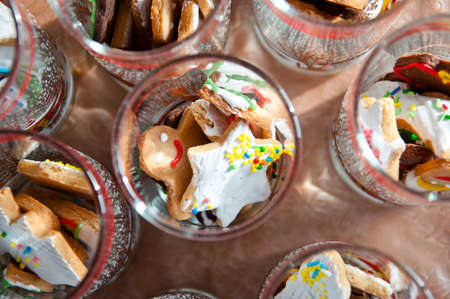 tasty christmas or xmas biscuits or cookies for new year with white glaze and icing with colorful sprinkles on ginger baked pastry decorated in winter glassesの写真素材