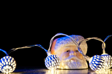 christmas or xmas decoration of new year toys decorated with garland lamps illumination and santa claus white color on black background, copy spaceの写真素材