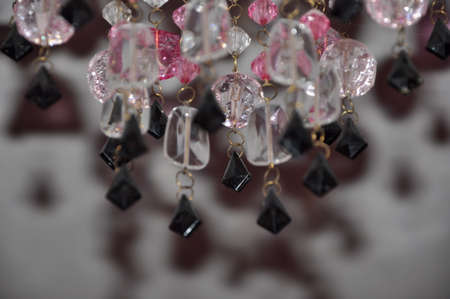 beautiful crystal or gemstones from plastic or glass white pink and black color on chain of chandelier lamp or lustre on blurred or defocused background, closeupの写真素材
