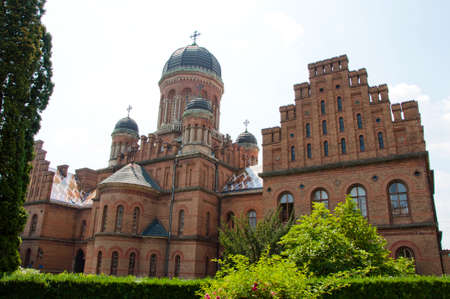 beautiful historical building of Chernivtsi national university religious seminary of red brick facade with green trees and bushes sunny outdoor in Ukraineの写真素材