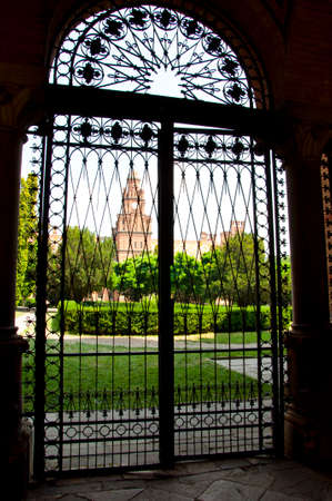 beautiful historical building of Chernivtsi national university religious seminary of red brick facade with green trees and bushes behind iron gates sunny outdoor in Ukraineの写真素材