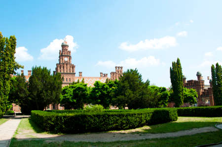 beautiful historical building of Chernivtsi national university religious seminary of red brick facade with green trees and bushes sunny outdoor in Ukraineの写真素材